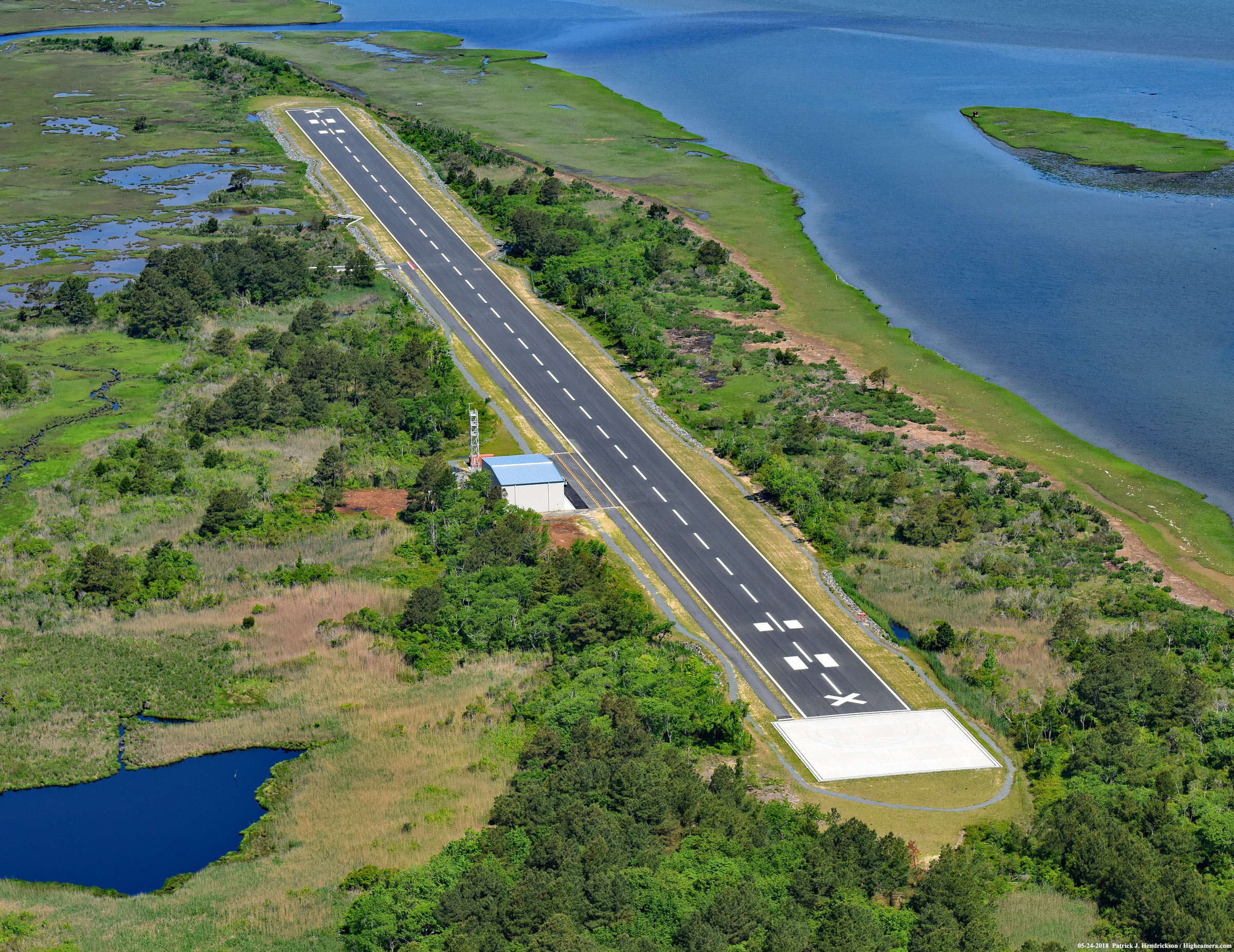 An east to west aerial photograph of the Unmanned Aerial System (UAS) Airstrip surrounded by vegetation and water, on the northern end of NASA Wallops Flight Facility's Wallops Island in Accomack County, Virginia. Photo courtesy of Patrick Hendrickson of HighCamera